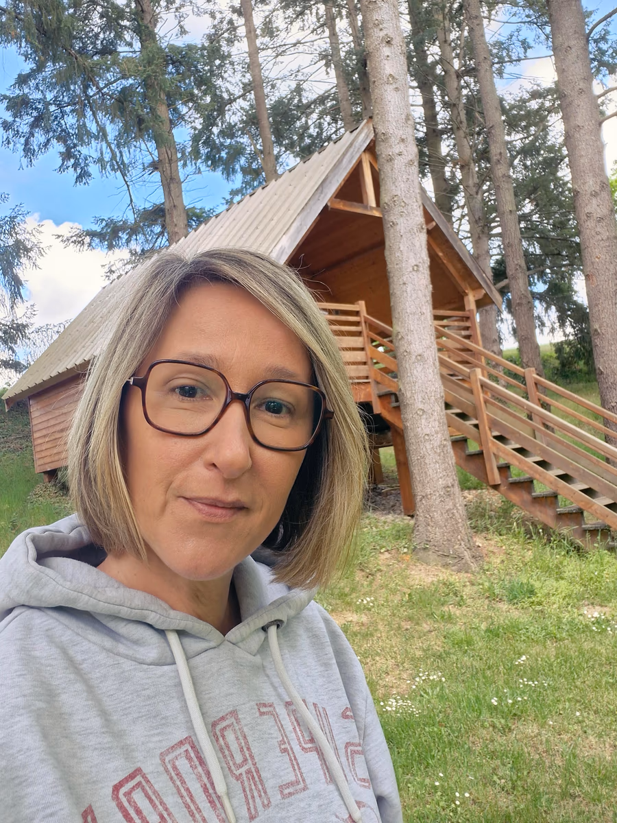 Céline devant une cabane en bois de la Petite Sapinière